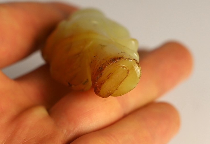 A rare Chinese yellow and russet jade figure of a boy holding a parrot, 18th/19th century, 5.6cm high, wood stand